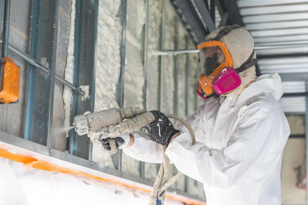 Commercial insulation installer applying material to an interior wall